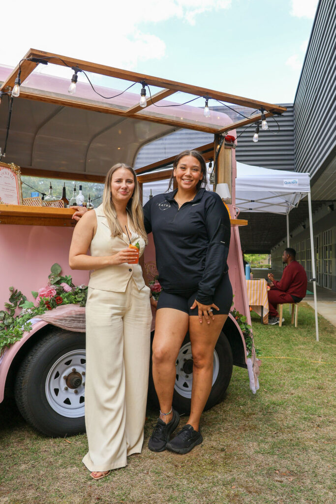 Organizer posing with vendor in front of vendor cocktail trailer